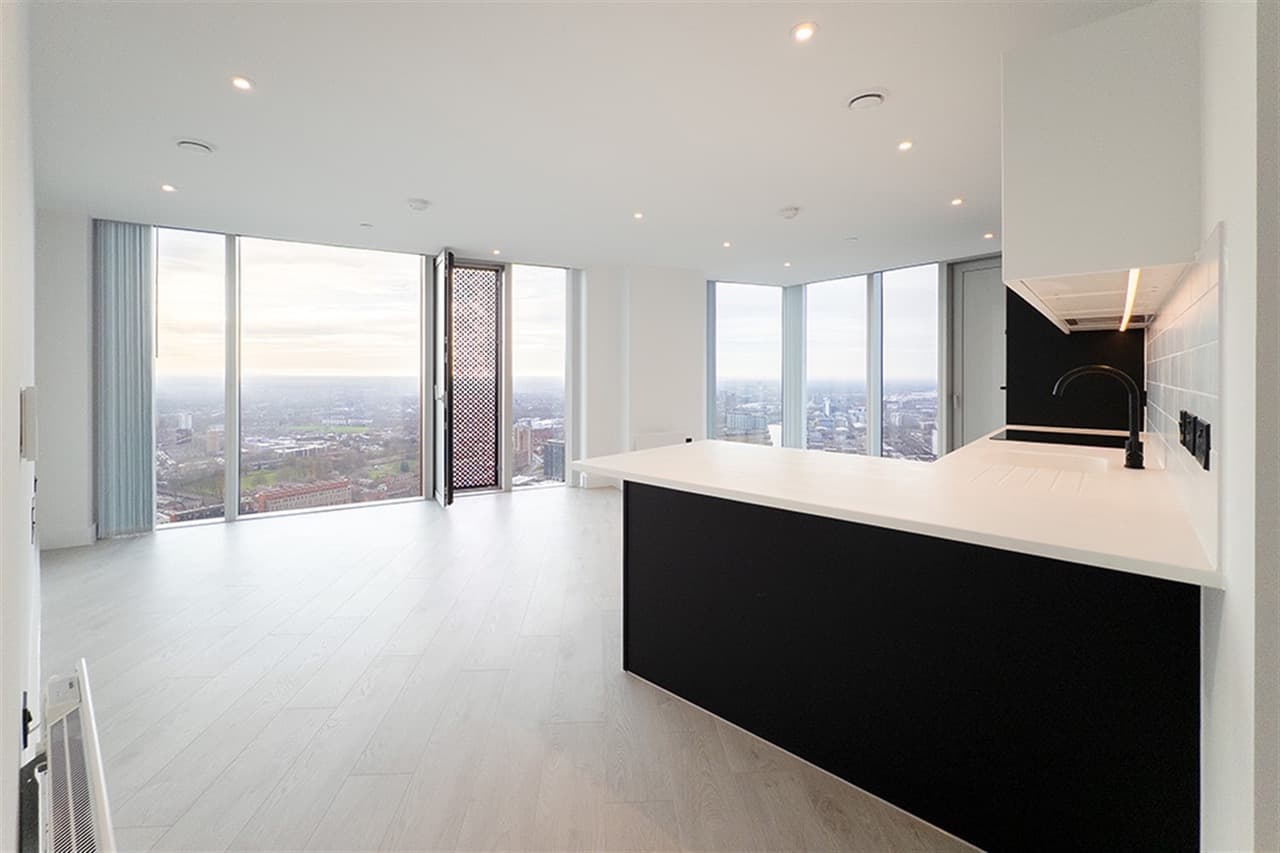 Open plan kitchen and living space in an apartment at Vista River Gardens, Manchester, with floor to ceiling windows overlooking the city